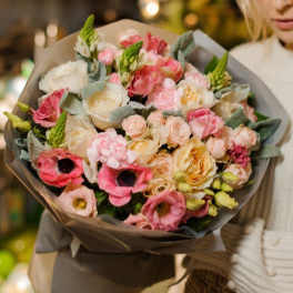Large bouquet of pink and cream flowers wrapped in gray paper