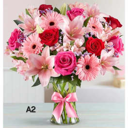 Pink and red mixed bouquet in a clear glass vase with a pink ribbon