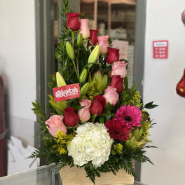 Tall bouquet of pink and red roses with white hydrangea in a wooden box