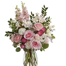 Pink roses and white flowers arranged in a clear glass vase