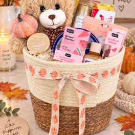 Fall gift basket with a teddy bear, pumpkin decor, and beauty products