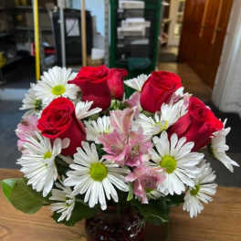 Red roses and white daisies in a dark glass vase