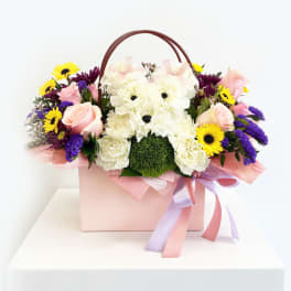 Pink and white floral arrangement in a gift box with a teddy bear face