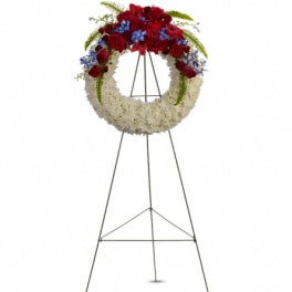 Standing funeral wreath with red, white, and blue flowers on an easel