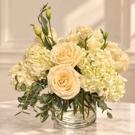 Cream roses and white hydrangeas in a clear glass vase