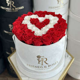 Red and white roses arranged in a heart shape in a white hat box