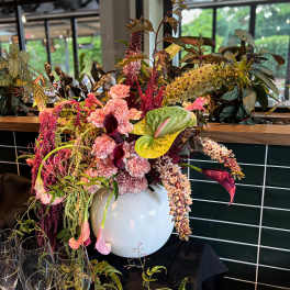 Large floral arrangement in a white vase with pink and burgundy blooms