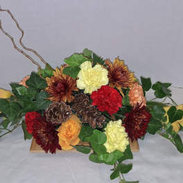 Low floral arrangement with chrysanthemums, roses, and ivy in a wooden container