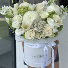 White rose and ranunculus bouquet in a round hat box with ribbon