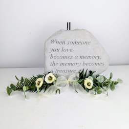 Memorial stone with white flowers and greenery arranged at the base