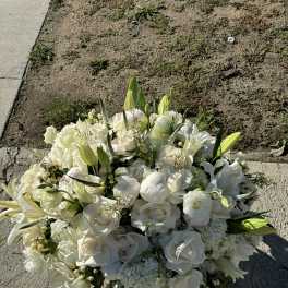 White floral bouquet with lilies and roses on pavement