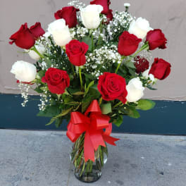 Bouquet of red and white roses in a glass vase with a red ribbon
