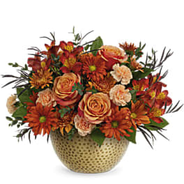Orange and peach flower arrangement in a textured ceramic vase