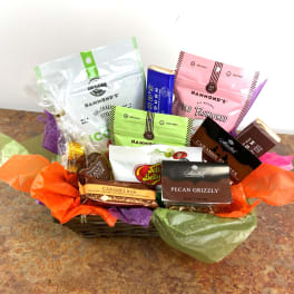 Basket of assorted candy and snack packages with colorful tissue paper