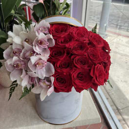 Red roses and pale pink orchids in a white round box