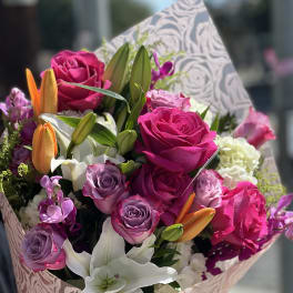Bouquet of pink and purple roses with white lilies and orange buds