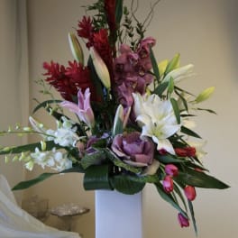 Tall mixed floral arrangement in a white rectangular vase
