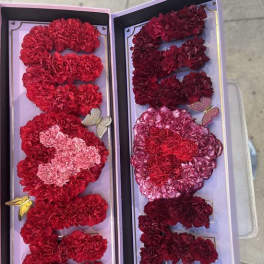 Two open gift boxes filled with red and pink carnation letters