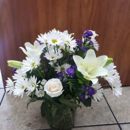 White daisies, lilies, and a rose in a glass vase