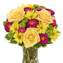 Yellow roses and bright daisy flowers in a clear glass vase