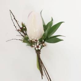 White candle boutonniere with green leaves and small berries