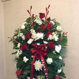 Standing funeral spray with red and white flowers and a burgundy ribbon