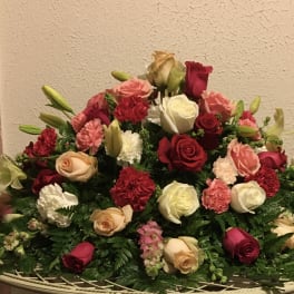 Large mixed bouquet of roses, lilies, and carnations in a low basket
