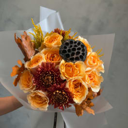 Bouquet of orange roses and burgundy mums with dried leaves