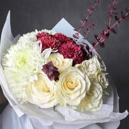 Bouquet of white roses and burgundy chrysanthemums with dark foliage