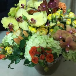 Mixed bouquet with orchids, hydrangeas, and roses in a dark vase