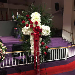 Standing funeral spray of white flowers and red roses with a red ribbon