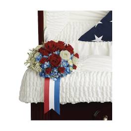 Red, white, and blue floral arrangement on a white-draped casket
