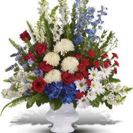 Mixed red, white, and blue floral arrangement in a white vase