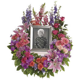 Floral memorial wreath with a framed portrait in the center