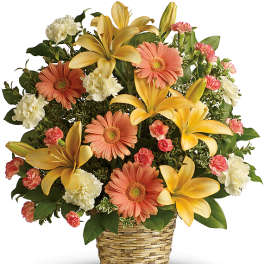 Mixed bouquet of yellow lilies, peach gerbera daisies, and white carnations in a woven basket