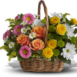 Basket arrangement of roses, daisies, and mums in pink, yellow, orange, and white