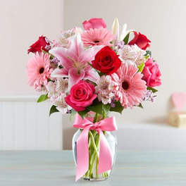 Pink and red mixed bouquet in a glass vase with a pink ribbon