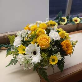Yellow and white mixed flower arrangement in a white container