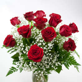 Red roses arranged in a clear glass vase with white baby's breath