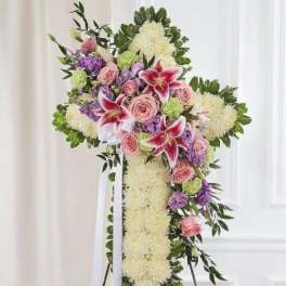 Standing floral cross with pink roses, lilies, and white blooms