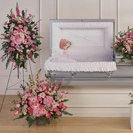 Pink floral funeral casket spray with matching arrangements and heart wreath