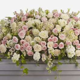 Large pastel rose arrangement with white blooms and trailing greenery