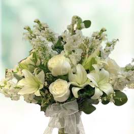 White floral bouquet in a clear glass vase with a sheer ribbon