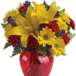 Yellow lilies and daisies in a red glass vase