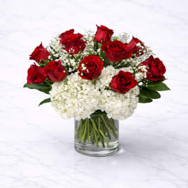 Red roses and white hydrangeas in a clear glass vase