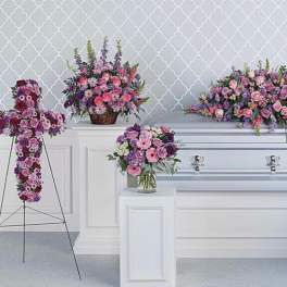 Funeral casket surrounded by pink and purple floral sprays