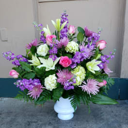 Pink roses, white lilies, and purple flowers in a white vase