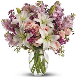 Pink roses and white lilies arranged in a clear glass vase