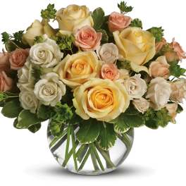Bouquet of cream, peach, and yellow roses in a clear glass vase