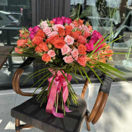 Large bouquet of pink and orange roses tied with a pink ribbon